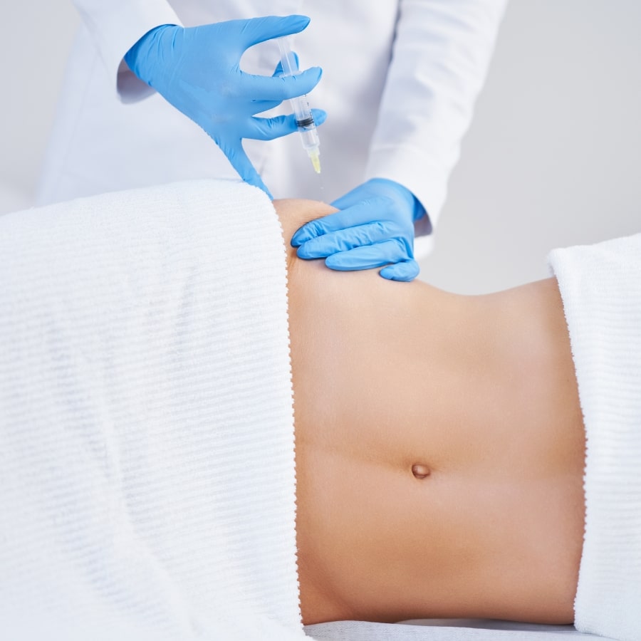 Injektion in den Bauchbereich einer Patientin durch medizinisches Fachpersonal – Anwendung der Fett-weg-Spritze zur lokalen Fettreduktion.